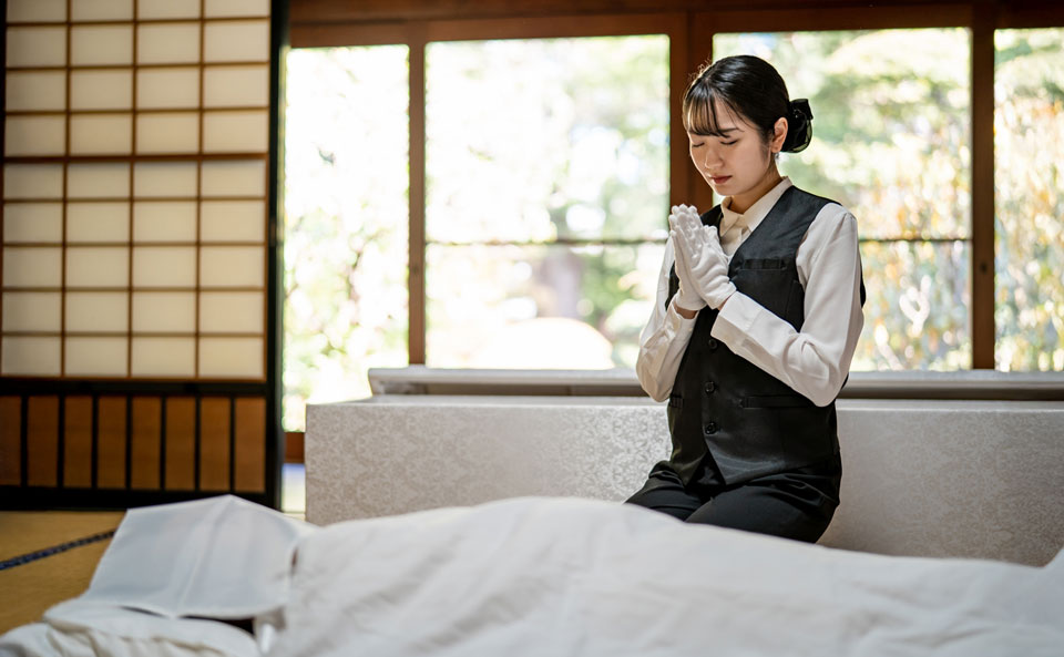 葬儀撮影サービス｜燈のスタッフが和室で遺族に手を合わせる葬儀撮影の様子