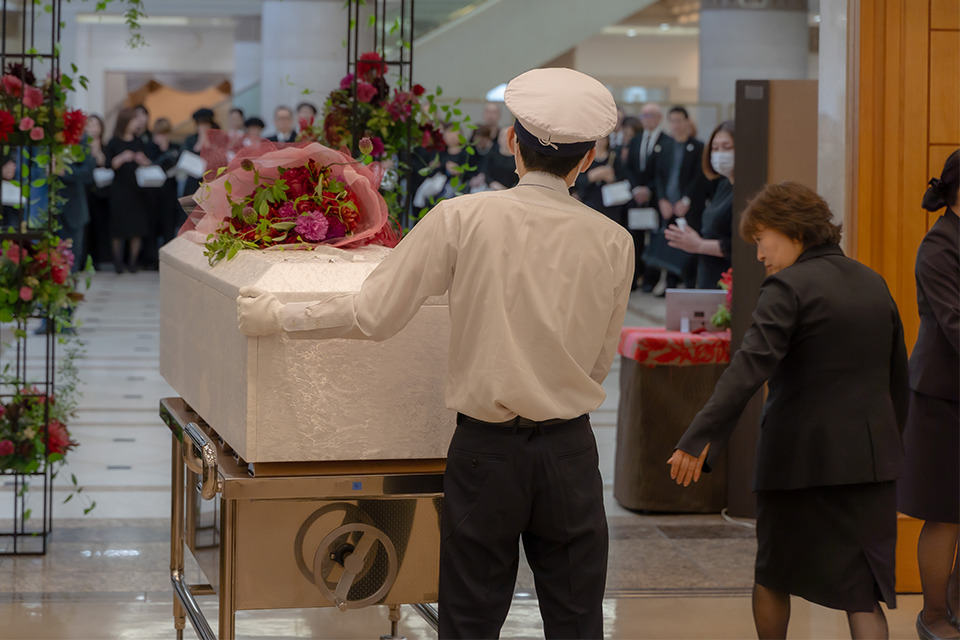葬儀撮影サービス｜燈が白い棺に花を添える葬儀撮影シーン