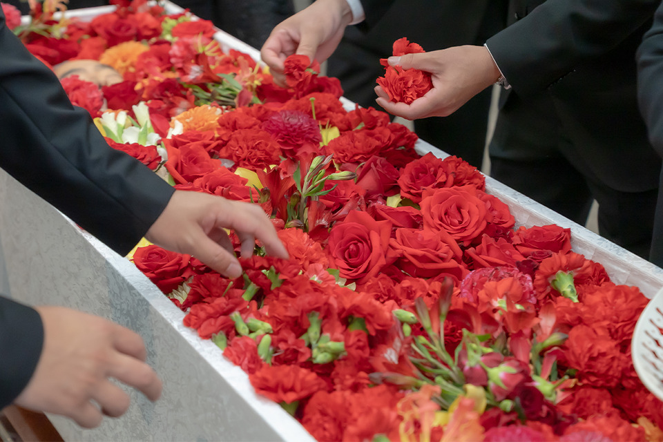 葬儀撮影サービス｜燈が祭壇の赤い花で故人を見送る焼香の瞬間を静かに撮影している